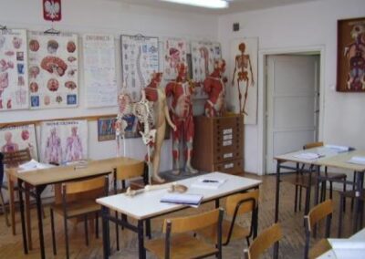 widok sali dydaktycznej przed remontem z wiszącymi na ścianach planszami obrazującymi elementy ludzkiego organizmu, oraz stojącymi kilkoma modelami układu mięśniowego
